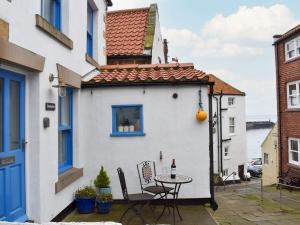 ein kleines weißes Haus mit einem Tisch und Stühlen in der Unterkunft Sunnydene in Staithes