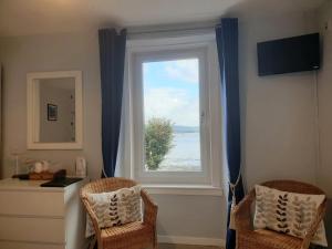 una finestra con tende blu e due sedie in una stanza di Carnaburg Guesthouse a Tobermory
