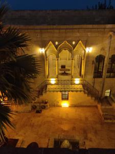 un edificio antiguo con una escalera en un patio por la noche en Muzepotamia Butik Otel en Sanlıurfa