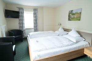 a bedroom with a bed with white sheets and a window at Hotel Haus Burg Metternich in Beilstein