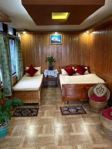 Habitación con 2 camas y mesa con alfombras en Raibas Homestay, en Darjeeling