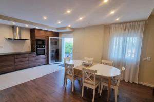 a kitchen and dining room with a white table and chairs at Casinha da Belavista in Arcos de Valdevez