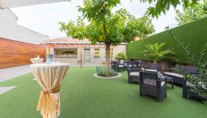 a patio with green grass and chairs and a tree at El Patio in La Almunia de Doña Godina
