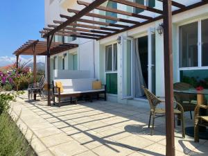 a patio with a wooden pergola and a table and chairs at Crystal Bay View Apartment in Kalogrea