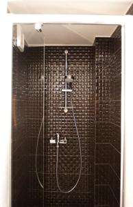 baño con ducha de azulejos negros en Nice & Cheap Apartment and FREE parking, en Riga