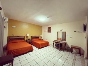 a hotel room with two beds and a desk at Hotel Las Fuentes in Los Mochis