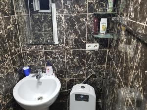Baño de azulejos negros con lavabo y aseo en Silk House, en Tiflis