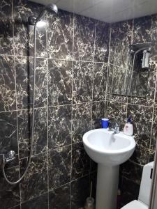 baño de azulejos negros con lavabo y ducha en Silk House, en Tiflis