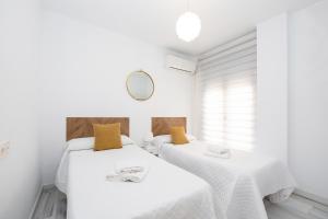 2 camas en una habitación blanca con espejo en Grace Apartments - 3 bedroom City Centre, en Granada