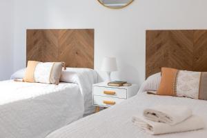 a bedroom with two beds with white sheets and a wooden headboard at Grace Apartments - 3 bedroom City Centre in Granada