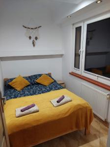 a bedroom with a yellow bed with two towels on it at Pokoje u Eli in Szczawnica