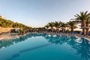 einen großen Pool mit Stühlen und Palmen in der Unterkunft Mediterraneo Hotel in Hersonissos