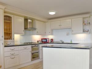 a white kitchen with white cabinets and a counter at Seaview Apartment - 21 Spinnakers in Newquay