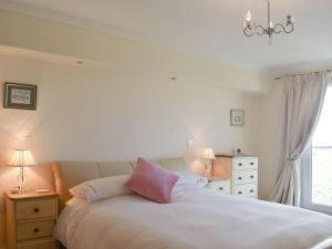 a bedroom with a bed with a pink pillow on it at Seaview Apartment - 21 Spinnakers in Newquay