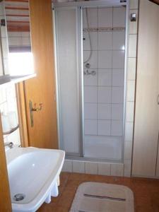 ein Badezimmer mit einer Dusche, einer weißen Badewanne und einem Waschbecken in der Unterkunft Ferienhäuschen Kathrein in Ehenbichl