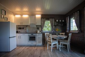 a kitchen with white appliances and a table with chairs at Medsedis Plateliai in Plateliai