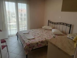 a small bedroom with a bed with a floral bedspread at KALIPSO STUDIOS in Nikiti