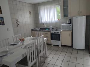 cocina con nevera, mesa y sillas en residencial pilati en Bombinhas