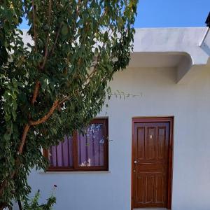 uma casa branca com uma porta de madeira e árvores em La Medusa Gardens em Iskele