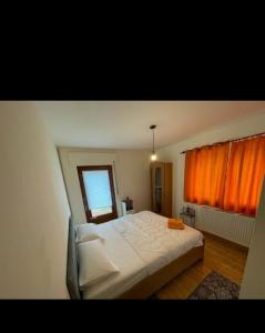 um quarto com uma cama branca e uma cortina laranja em Osteria Mediterranean em Freirachdorf