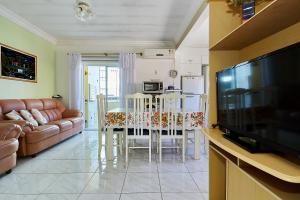 un salon avec un canapé, une table et une télévision dans l'établissement 1040 - Departamento 2 quartos na Rua Pirajica . 200 m da Praia Bombinhas Centro, à Bombinhas
