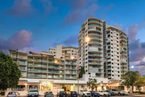 um grande edifício de apartamentos com carros estacionados num parque de estacionamento em City Quays Accommodation em Cairns