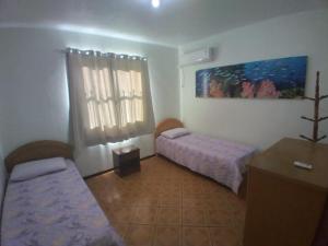 Habitación pequeña con 2 camas y mesa. en residencial pilati en Bombinhas