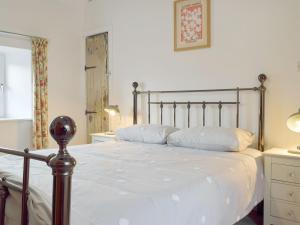 a bedroom with a large bed with white sheets at Horton View Cottage in Ferryside