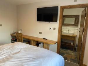 a bedroom with a bed and a desk with a television on the wall at Maypole Farm, Cawood in Selby