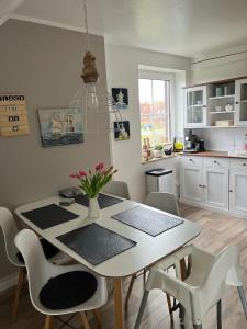 uma cozinha com uma mesa e cadeiras brancas e uma sala de jantar em Place to be Fehmarn em Fehmarn