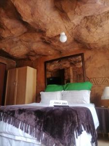a bedroom with a large bed in a stone wall at Sikhula Sonke Guest House in Erasmus