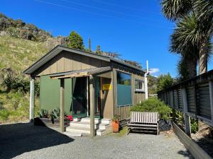 um pequeno edifício com um banco à frente em Hydrangea Cottages em Punakaiki