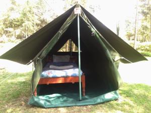 a bed in a black tent in the grass at Triple Eden Resort - Naivasha in Naivasha