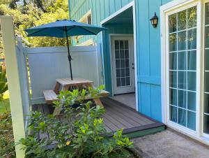 ein blaues Haus mit einer Bank und einem Regenschirm in der Unterkunft Heavenly Hana Paradise in Hana
