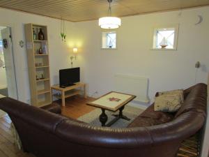 a living room with a leather couch and a table at DeLay's Guest House in Ängelholm