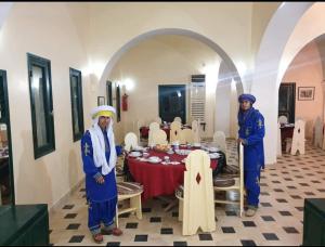 dos personas parados frente a una mesa en una habitación en Hotel Pansy, en Qaşr Ghīlān