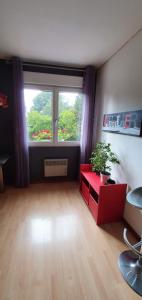 uma sala de estar com uma mesa vermelha e uma janela em Chambre des Acacias 