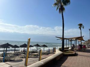 a beach with umbrellas and chairs and the ocean at Fuengirola Paseo Marítimo 27 in Fuengirola