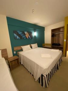 a bedroom with a large white bed with a green wall at Solar das Águas Resort in Olímpia