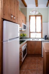 a kitchen with a white refrigerator and wooden cabinets at Colonia Apartamento Rural in Bellmunt de Ciurana