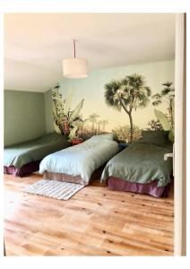 - 2 lits dans une chambre avec des palmiers sur le mur dans l'établissement Jolie maison entre mer et Narbonne, à Narbonne