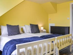 a white bed in a room with yellow walls at Greve Cottage in Marykirk