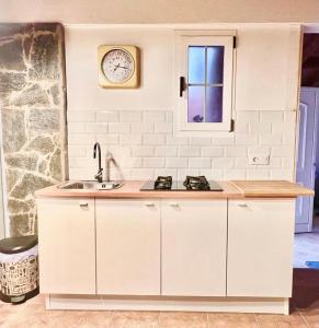 una cocina con fregadero y un reloj en la pared en El Alegato Casa de Invitados en Antigua