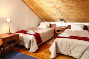 a bedroom with two beds and a wooden ceiling at Nobuta Vendégház in Verőce