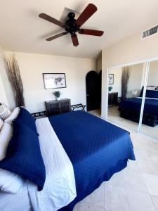 a bedroom with a blue bed and a ceiling fan at Stunning oceanfront condo on usable Sandy Beach in Rosarito