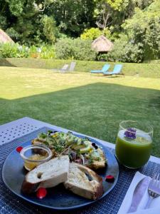 a blue plate with a sandwich and a glass of green juice at The Haven - Hotel & Spa, Health and Wellness Accommodation - Adults Only in Boquete
