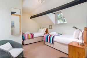 a bedroom with two beds and a chair and a window at Oak Cottage Chapel Stile in Chapel Stile