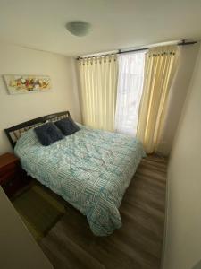 1 dormitorio con 1 cama con 2 almohadas y ventana en Departamento en playa, en La Serena