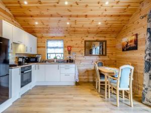 a kitchen with wooden walls and a table and chairs at Cabin Hideaways, Glencraig - Uk38359 in Mattishall