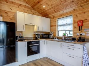 a kitchen with white cabinets and a black refrigerator at Cabin Hideaways, Glencraig - Uk38359 in Mattishall